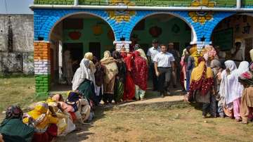People wait in queues to cast their votes at a polling booth during the Haryana panchayat elections, in Mewat district.
