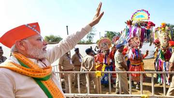 PM Modi waves at supporters during a public meeting at Kaprada in Valsad district.