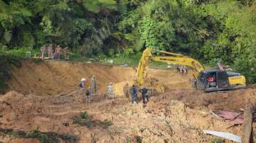 Rescue teams use a backhoe to continue the search for victims caught in a landslide.