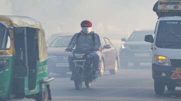Commuters move through smoke in New Delhi.