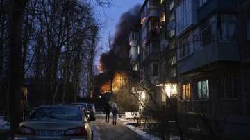Residents watch at a burning infrastructure project hit during a Russian drone night strike in Kyiv, Ukraine.