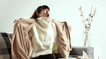 Representative image of a woman feeling cold and wrapping herself in blanket