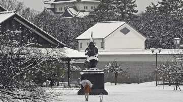 A resident shovels snow off around a car at a parking lot in Kitami city Hokkaido prefecture in northern Japan. 