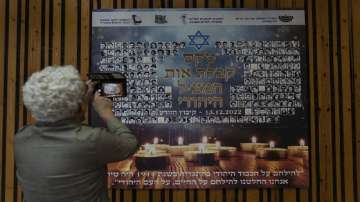 A woman photographs a poster in memory of members of the Zionist youth movement underground in Hungary during the Holocaust at a ceremony awarding the Jewish Rescuers Citation.
