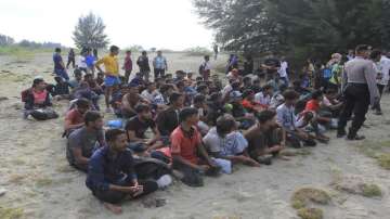Ethnic Rohingya people sit on a beach after they landed in Aceh Besar.