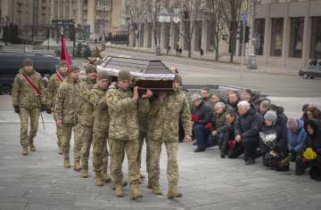 People kneel as the Ukrainian servicemen carry the coffin of their comrade Oleh Yurchenko killed in a battlefield with Russian forces in the Donetsk region during a commemoration ceremony in Independence Square in Kyiv, Ukraine.