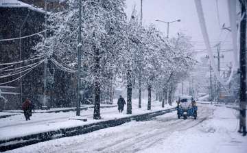 Commuters on a snow-covered road during heavy snowfall in Srinagar. 