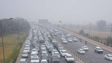 Vehicles stuck in traffic jam on a road amid low visibility due to fog on a cold winter morning, in New Delhi.