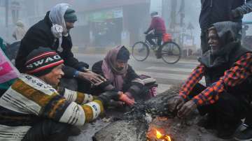 People sit around a bonfire to warm themselves on a cold and foggy winter morning, in Kanpur.