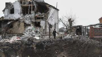 A woman stands on top of a crater next to a destroyed house after a Russian rocket attack in Hlevakha, Kyiv region, Ukraine. 