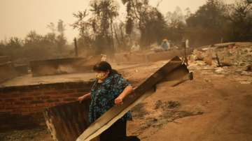 

A woman clears debris from a landscape of charred remains in Santa Ana, Chile,