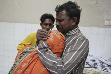 People mourn next to the body of their family member, who died in the stampede, at a morgue, in Karachi.

