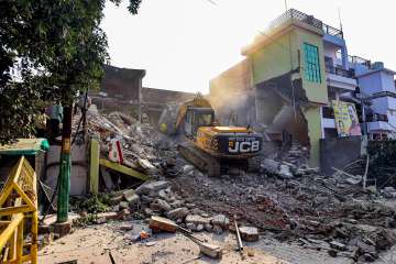 Prayagraj: A policeman guards as a Prayagraj Development Authority bulldozer demolishes Arms shopkeeper Safdar Alis properties in the Chakiya area, in Prayagraj, Thursday, March 2, 2023. Ali is said to be a close aid of Atiq Ahmad.