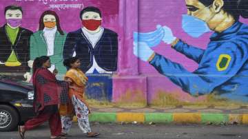 Women walk past a graffiti on a wall urging people to wear face masks in Mumbai.