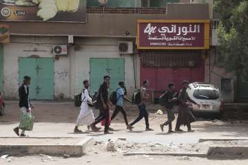 People walk past shuttered shops in Khartoum.