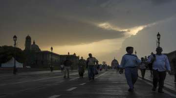 Government employees on the Kartavya Path as dark clouds are aeen in the sky, in New Delhi on Thursday evening.