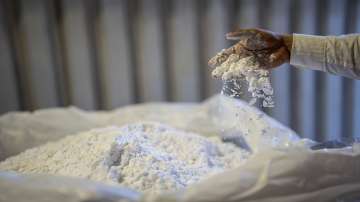 A worker stirs lithium with his hand at a processing plant.