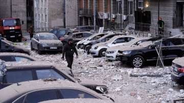 A police officer walks at the parking with damaged cars in front of a multi-story apartment building which was damaged during Russian attack in Kyiv