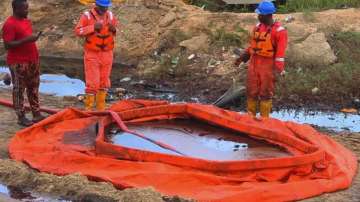 Workers stand by a container to collect oil spill waste, in Ogoniland, Nigeria