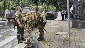 Servicemen of the Wagner Group military company talk to each other as they guard an area at the HQ of the Southern Military District in a street in Rostov-on-Don, Russia