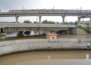 A Delhi Metro train passes by as the swollen Yamuna river floods low-lying areas.