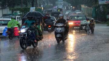 Commuters on a road amid rainfall, in Dehradun