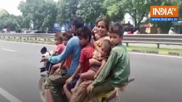 A man is seen riding a two-wheeler with 6 family members