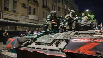 Members of Wagner Group military company sit atop of tank on street in Rostov-on-Don, Russia