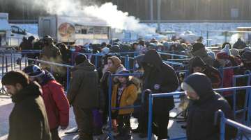 Migrants queue to receive hot food at a logistics center