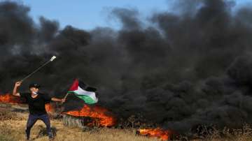 Palestinian protester uses sling shots to hurls stones during clashes with Israeli security forces