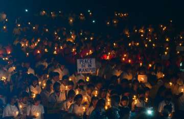 People holding placards and candles take part in a prayer service for peace in Manipur