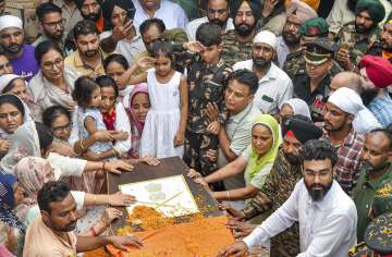 Son of Colonel Manpreet Singh salutes as family members and relatives mourn near his mortal remains before his last rites, at his native place in Mohali