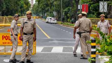 Police personnel stand guard at a barricaded road near Raisina Road ahead of the upcoming G20 Summit, in New Delhi