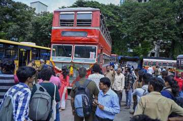 People click photos of a red non-AC double-decker bus of Brihanmumbai Electricity Supply and Transport (BEST), parked at a depot, in Mumbai