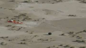 Image shared by NASA TV shows capsule released by the Osiris-Rex spacecraft lying on the surface near the parachute after landing on Earth.