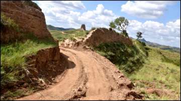 A dirt road passing through a damaged section of the Great Wall of China, in Youyu County.