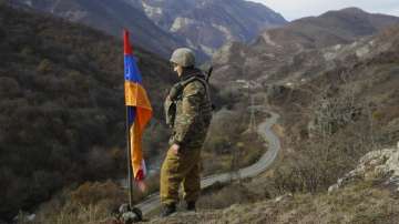 An Armenian soldier standing in front of Nagorno-Karabakh flag