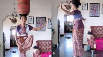 Woman performs stunts while dancing with gas cylinder on her head 