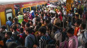 Security personnel attempt to control passengers rushing to board a train to travel home for the Chhath Puja festival, at New Delhi Railway Station