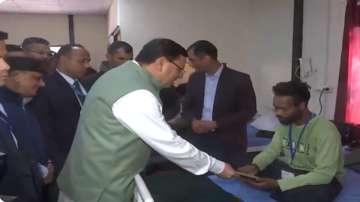 Uttarakhand Chief Minister Pushkar Singh Dhmai is handing over a relief cheque to a rescued worker at Chinyalisaur Community Health Centre in Uttarkashi.