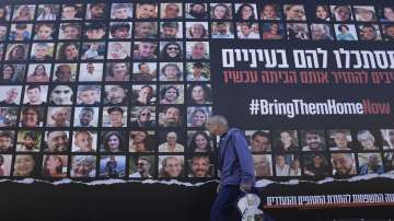 A man walks past a billboard calling for the return of about 240 hostages who were abducted during the Oct. 7, Hamas attack on Israel. in Jerusalem.