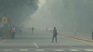 A man crosses a road, shrouded in a thick layer of fog, in New Delhi on Friday.