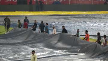 Ground staff places rain cover at Dr. Y.S. Rajasekhara Reddy ACA-VDCA Cricket Stadium.