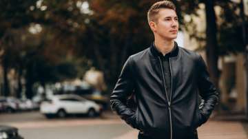 Man wearing a bomber jacket and walking down a road