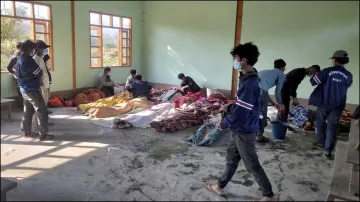 People clean the victims of airstrikes being shrouded in blankets at a building in Kanan village.