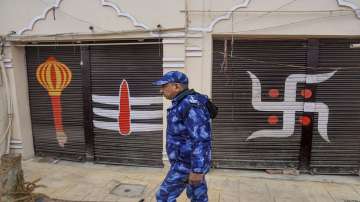A security official walks past closed shop shutters decorated with religious signs in Ayodhya. 