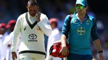 Usman Khawaja walks off the field alongside the Australian cricket team's physio.