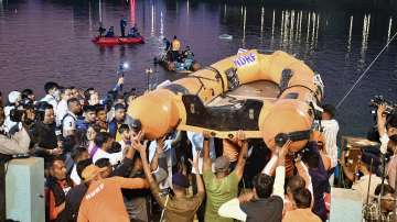 People gather during a rescue and search operation after a boat overturned in a lake in Vadodara.