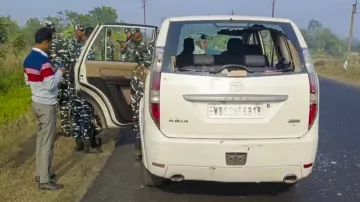 Security personnel with others stand near a vehicle which was allegedly damaged by the supporters of TMC leader Shajahan Sheikh during a raid by the ED officials at his residence, in North 24 Parganas district.