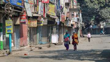 People walk past closed shops at market amid curfew at Banbhoolpura area 